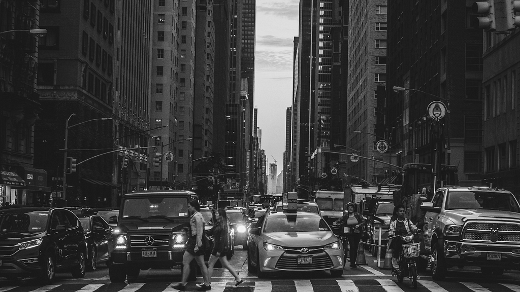 Traffic and people crossing a street, during rush hour in New York City.