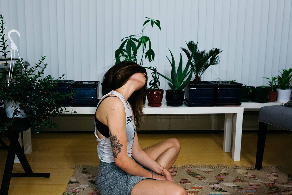 Woman doing yoga and surrounded by house plants
