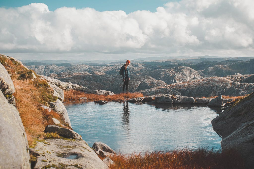 person standing in front of a small body of water with mountain view