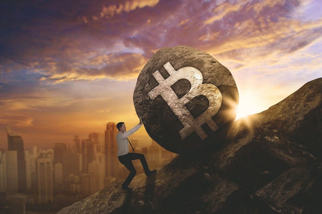 Man rolling boulder up a hill with the Bitcoin symbol engraved on its side.