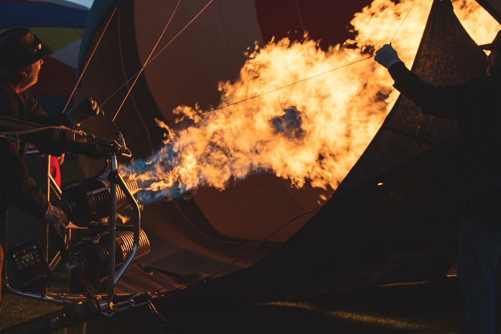 In what appears to be the earliest lightening of the dawn, a man is seen inflating a hot air balloon in preparation for its ultimate liftoff.