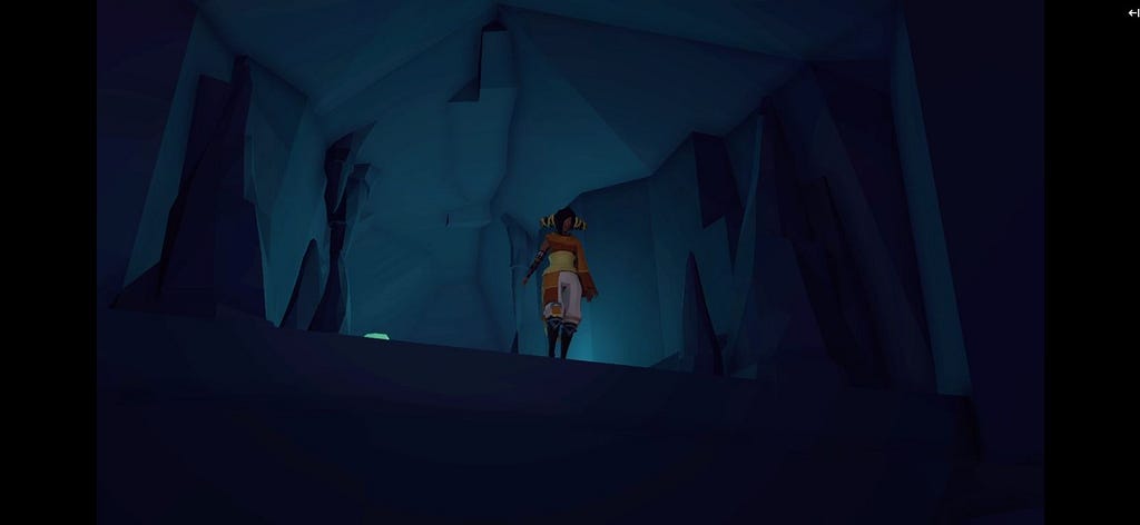 My orange-and-white-clad character stands on the edge of a drop off in a dark cave.