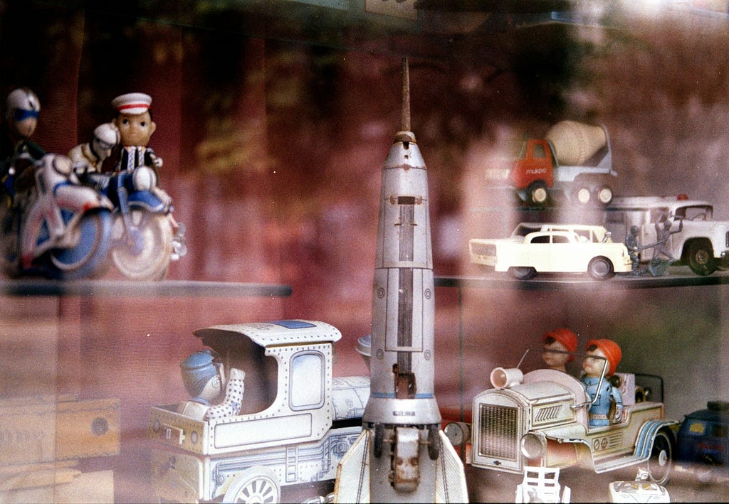 Collection of vintage toys in shop window with classic style toy rocket in the foreground