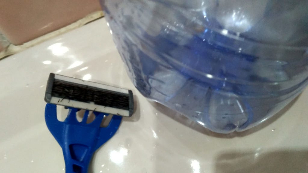 Razor clogged with hair and empty plastic water bottle