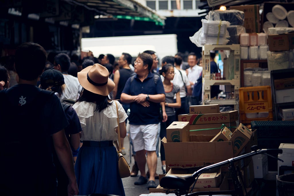 Crowd in an outdoor market with stacked boxes to the right