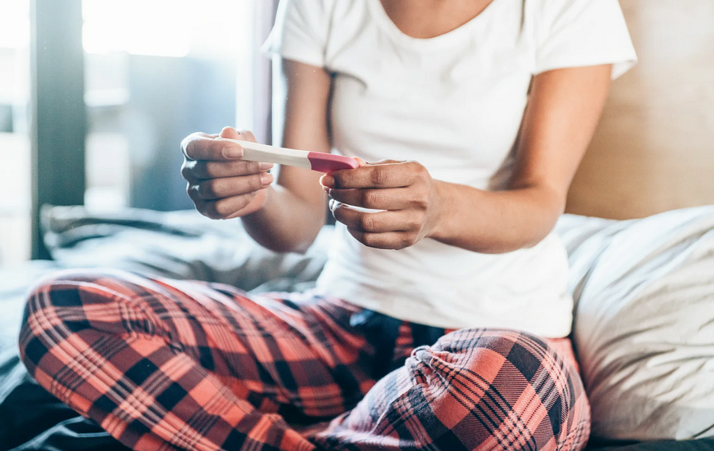 A dissapointed woman looks at a pregnancy test.