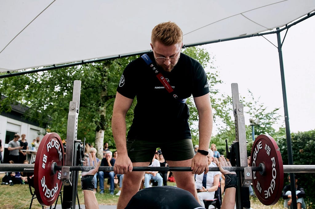 Sports psychologist and powerlifting coach Paul Schlütter, with an athlete during bench press at a competition