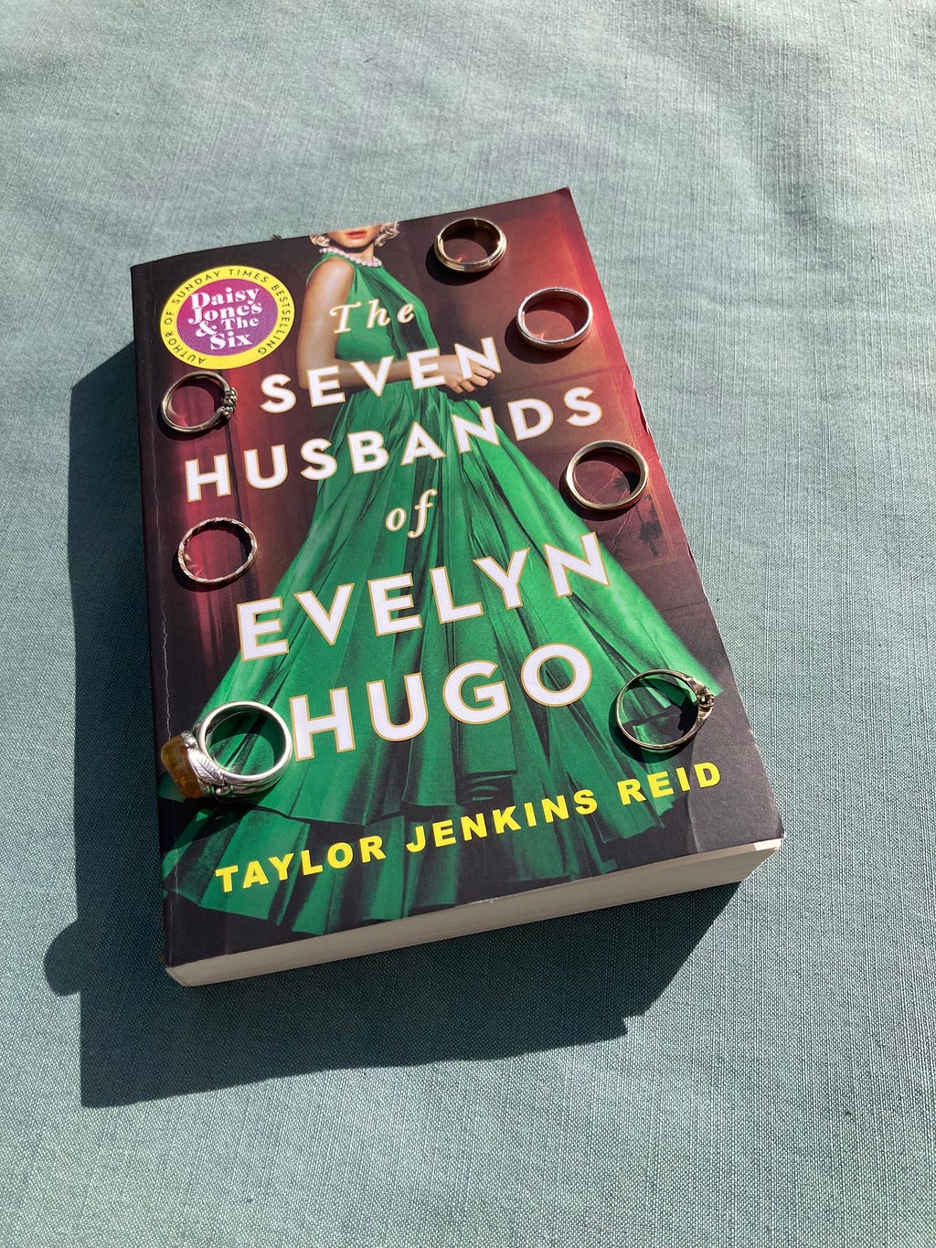 The book ‘The Seven Husbands of Evelyn Hugo’ by Taylor Jenkins Reid, with 7 rings placed on the cover