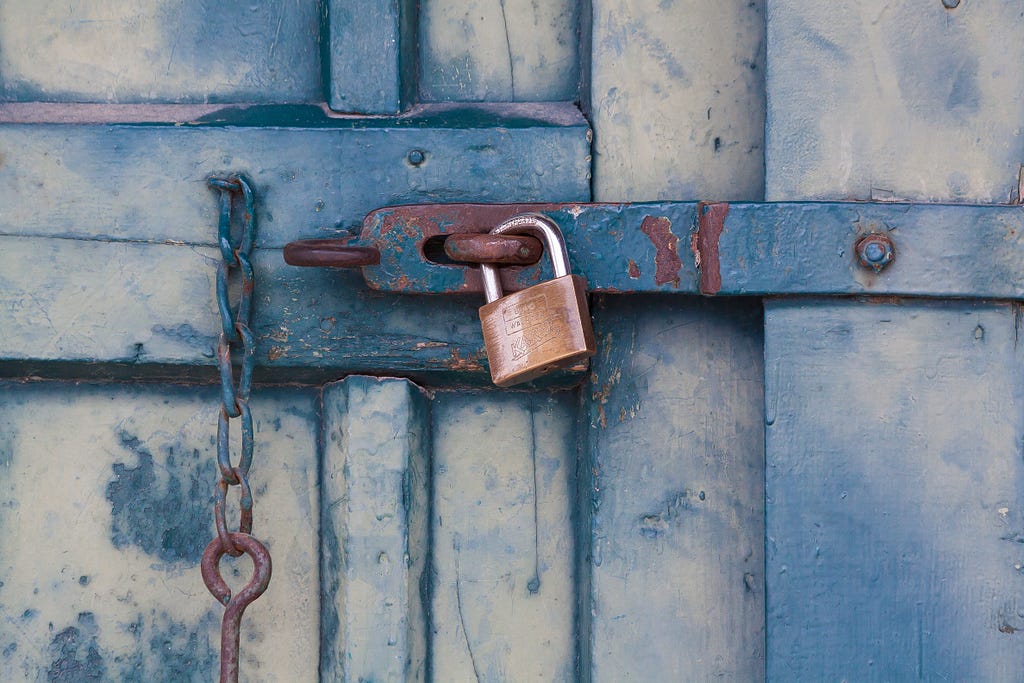 A padlock securing a rustic blue door.