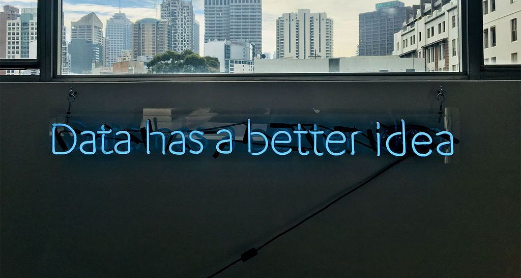 A frase "Data has a better idea" escrita em luz LED embaixo de uma janela com vista para predios altos.