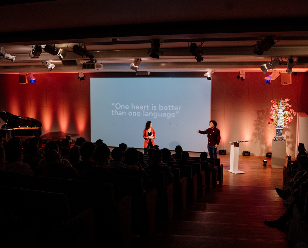 The picture features speaker Diego Snayers and presenter Ines Henriques Lopez standing in front of the presentation of the former, speaking to the audience