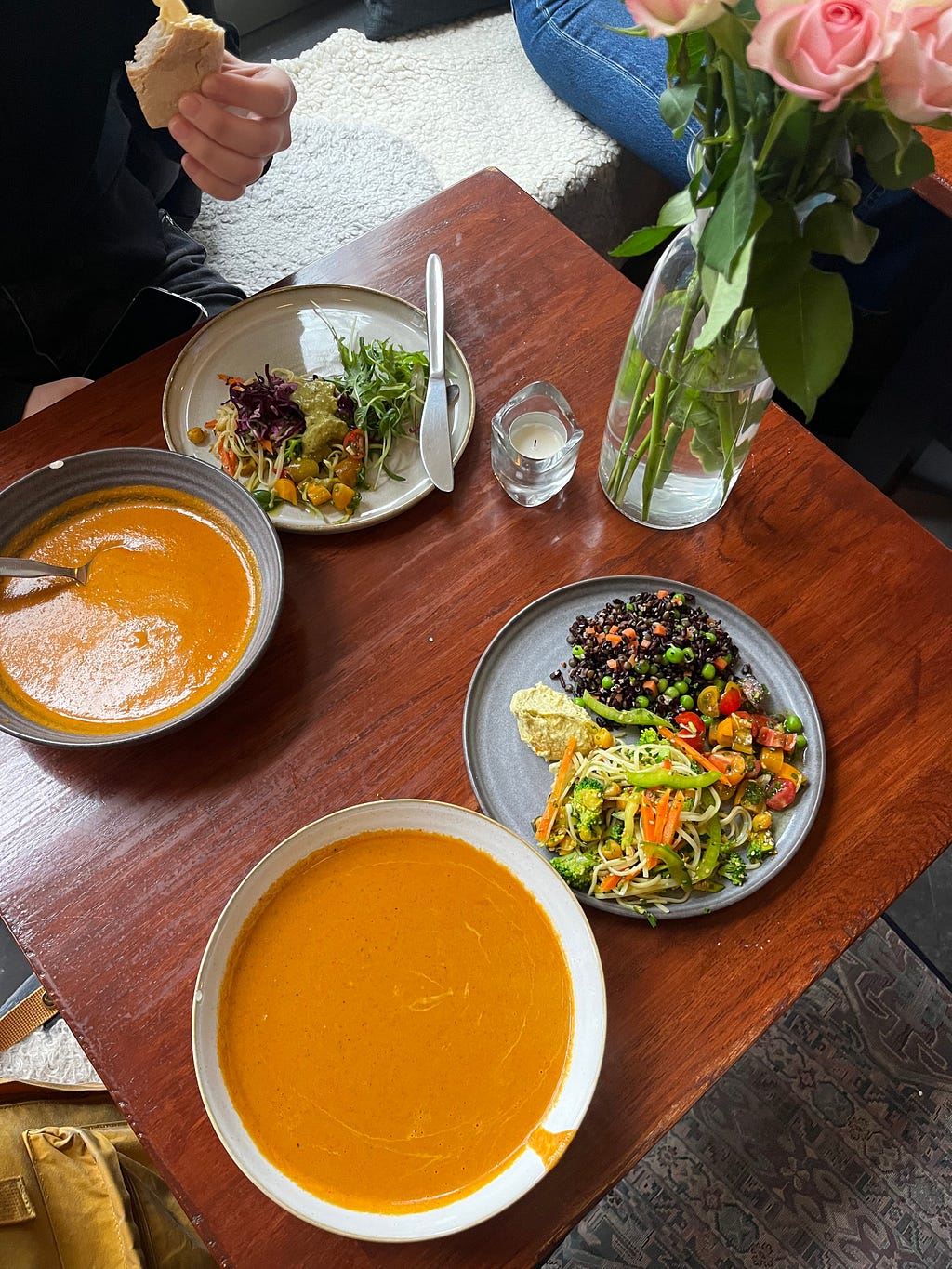 Photo displaying two bowls of tomato soup and two plates of fresh salad.
