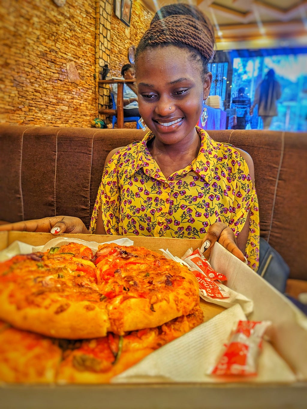 A beautiful Ugandan lady holding a carton of pizza