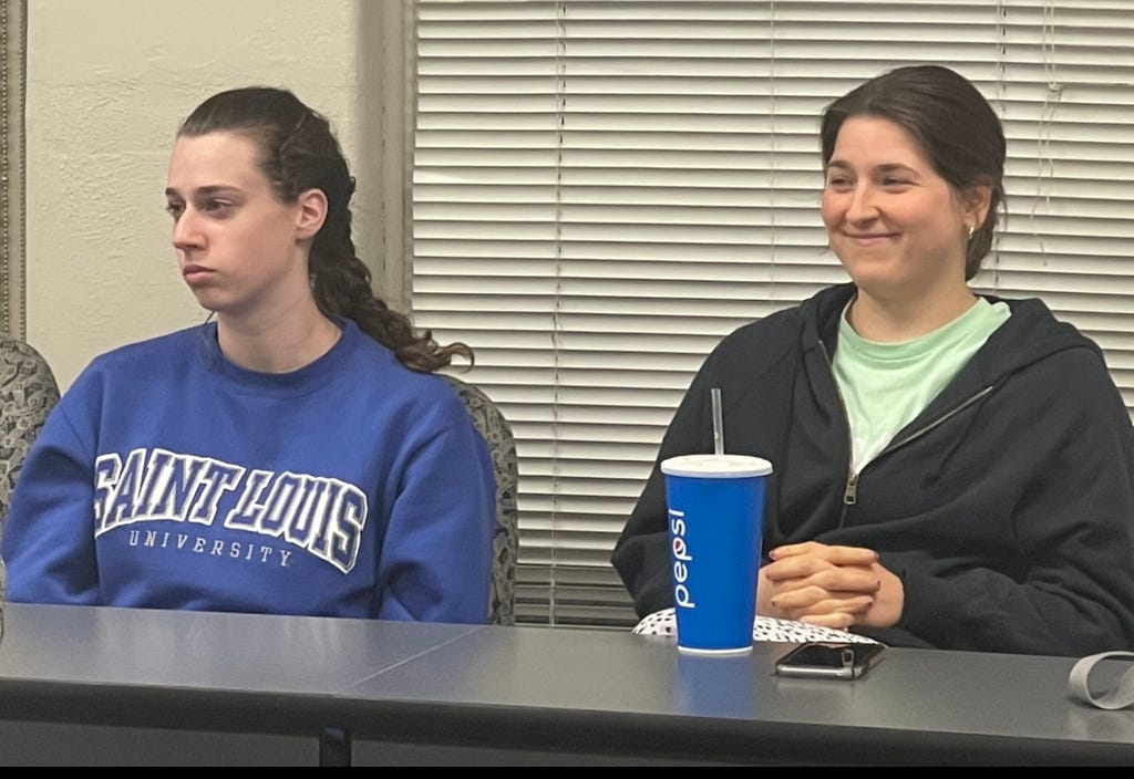 Two students listening to a presentation in a classroom and one of them is chuckling to themselves.