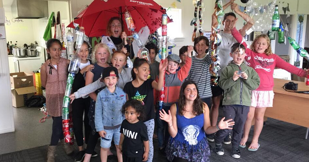 A group photo of kids in a with plastic bottle creations