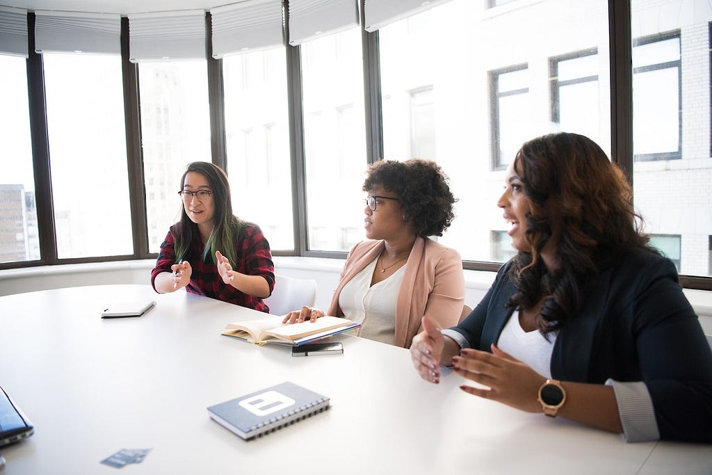 Three women working together at a conference table.
