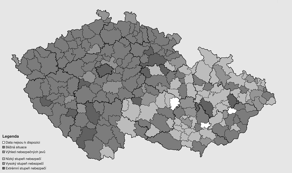 Černobílá reprodukce mapy České republiky rozdělené na okresy, které jsou vybarvené různě tmavými odstíny šedé.