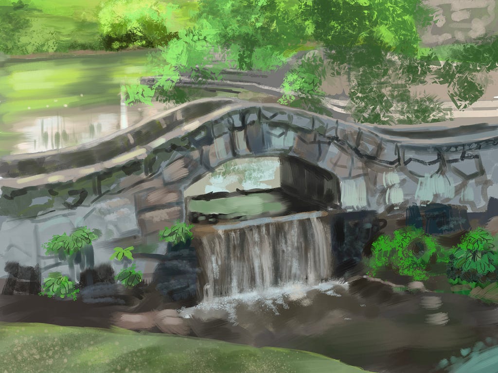 A stone footbridge in a park. Behind the bridge a pond can be seen. An opening in the stone below the foot path on the bridge allows the water from the pond to flow through and then becoming a waterfall, cascading a short distance down into a stream.