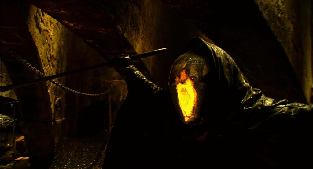 The Alchimist, bearing his mirror mask is seen brandighsing a small dagger in a dark environment.