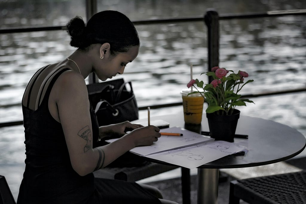 Money mindset: Woman writing in journal with flowers on thetable