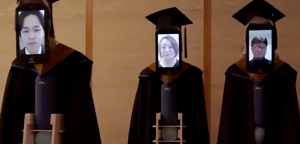 Tablets showing the faces of university students attached to telepresence robots wearings academic caps and gowns