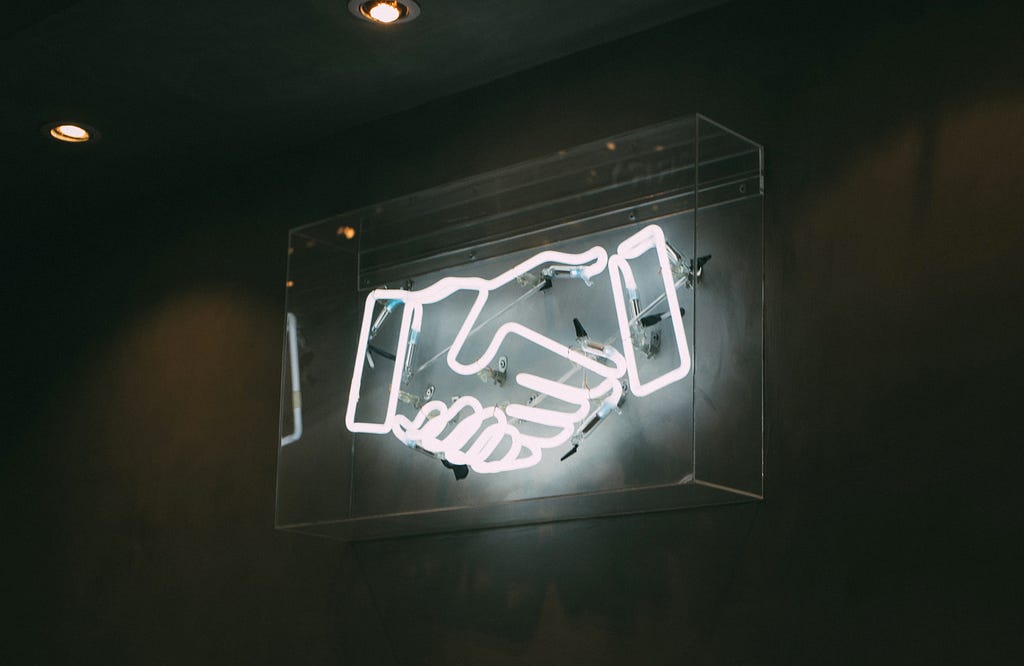 Um letreiro luminoso mostrando um aperto de mãos.