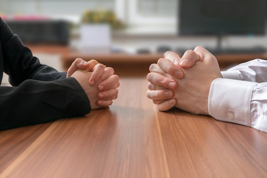 Hands coming together at a work desk to negotiate