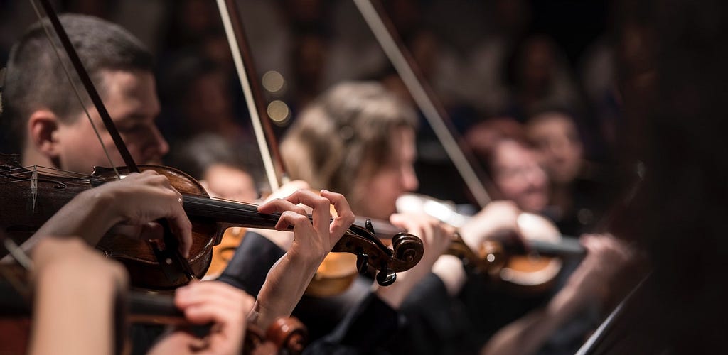 An Orchestra Playing a song. Violins and people fading into the background