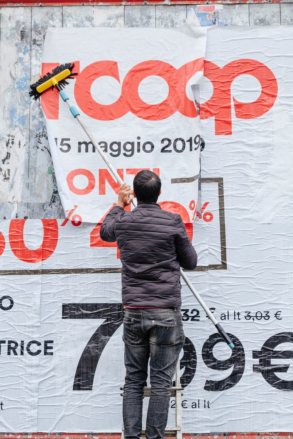 Uma pessoa colando um cartaz de descontos em uma parede.