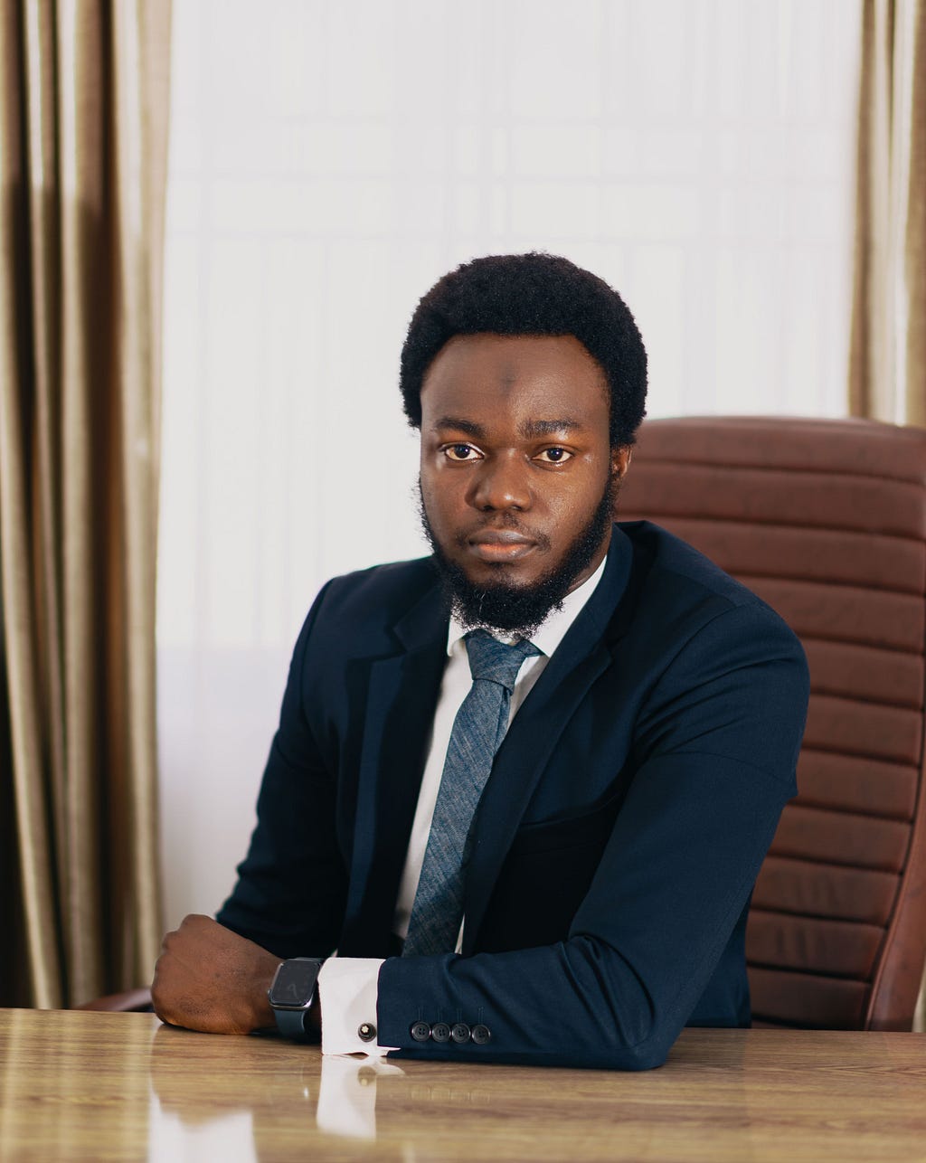 A man in a suit and tie sits at a desk