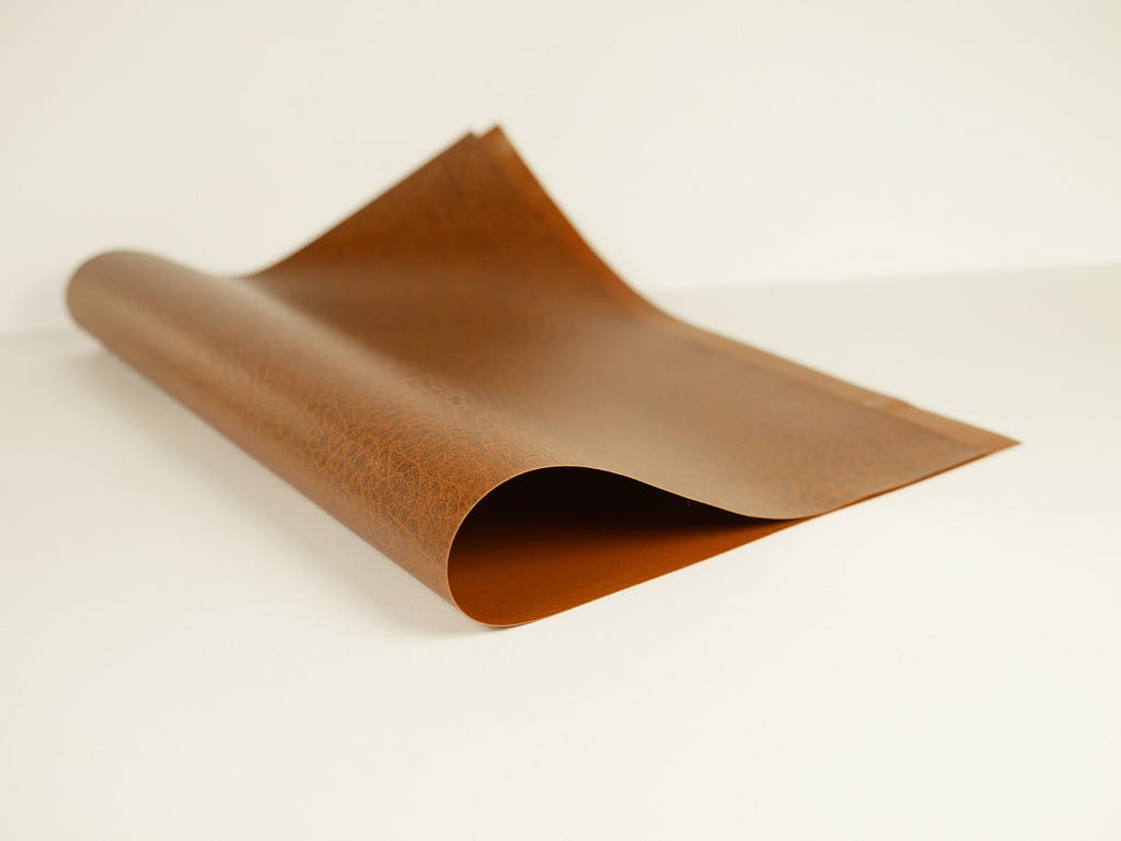 Pictured above is a piece of brown PVC material that is finished to mimic genuine leather.