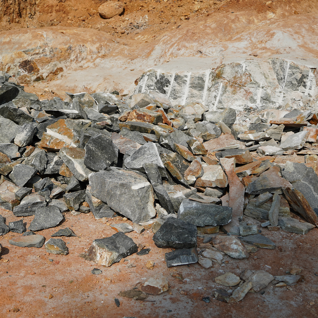 A pile of lithium and rubble at a mining site with exposed rocky earth in the background. The image highlights the raw materials involved in mining operations.