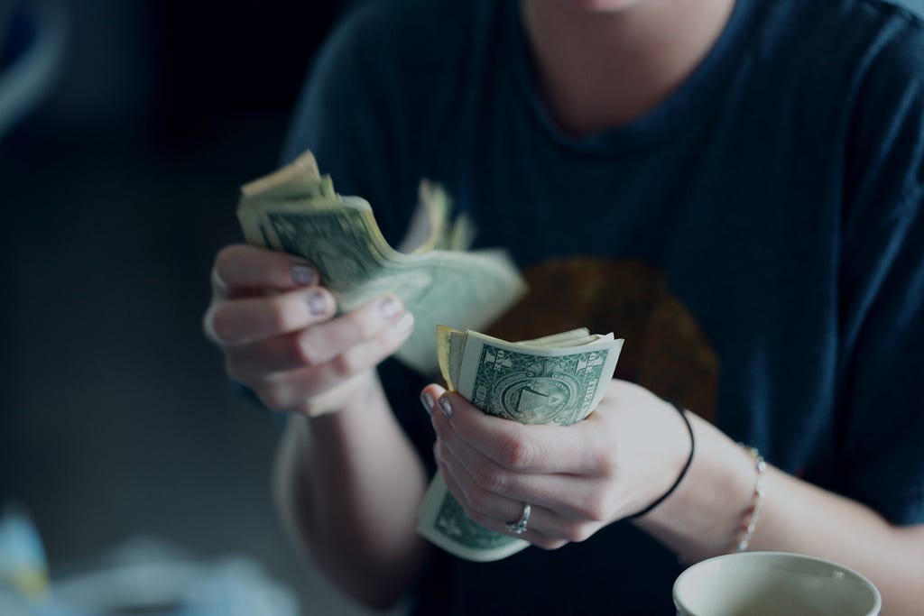 Hands counting American dollar bills.