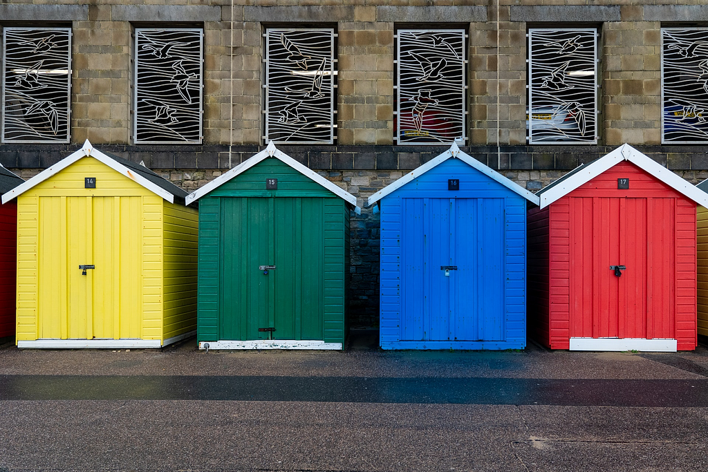A photo of four wooden booths, each with different colour.