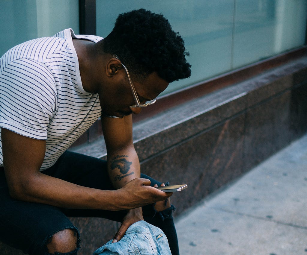 young Black person reading the news on their phone