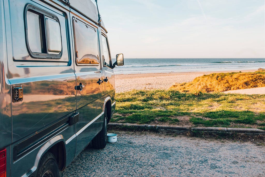 Green camper van parked by a beach