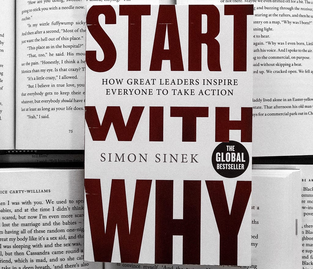 The print of Start With Why by Simon Sinek placed on top of several opened books.