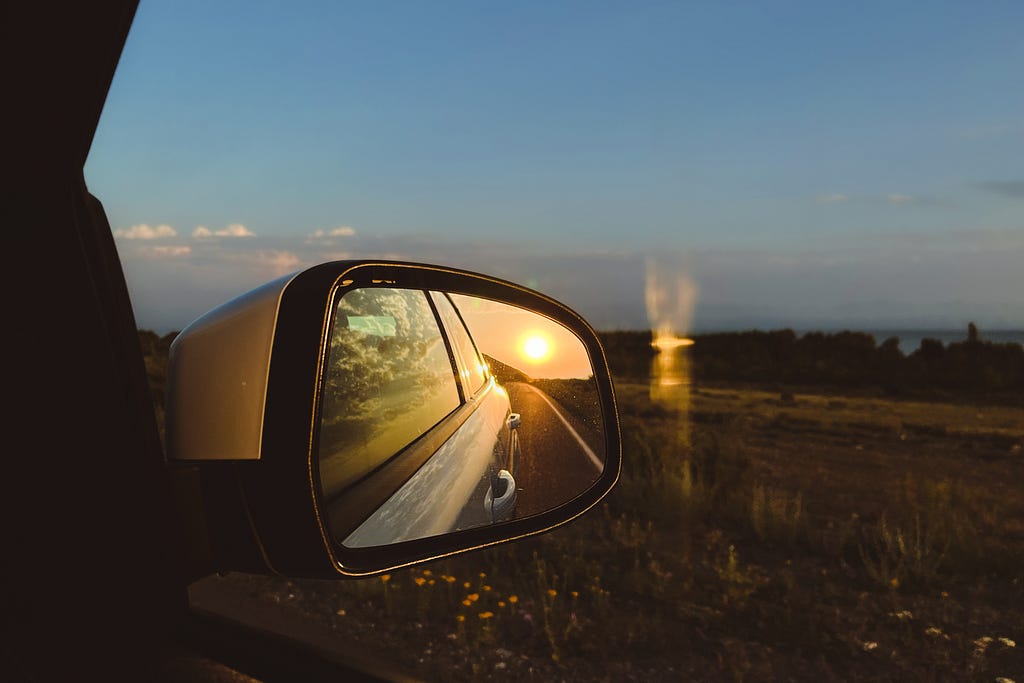 A view from a window car to the side mirror with sunset