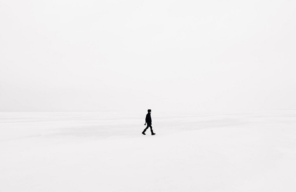 Solitary person walking across snowbank