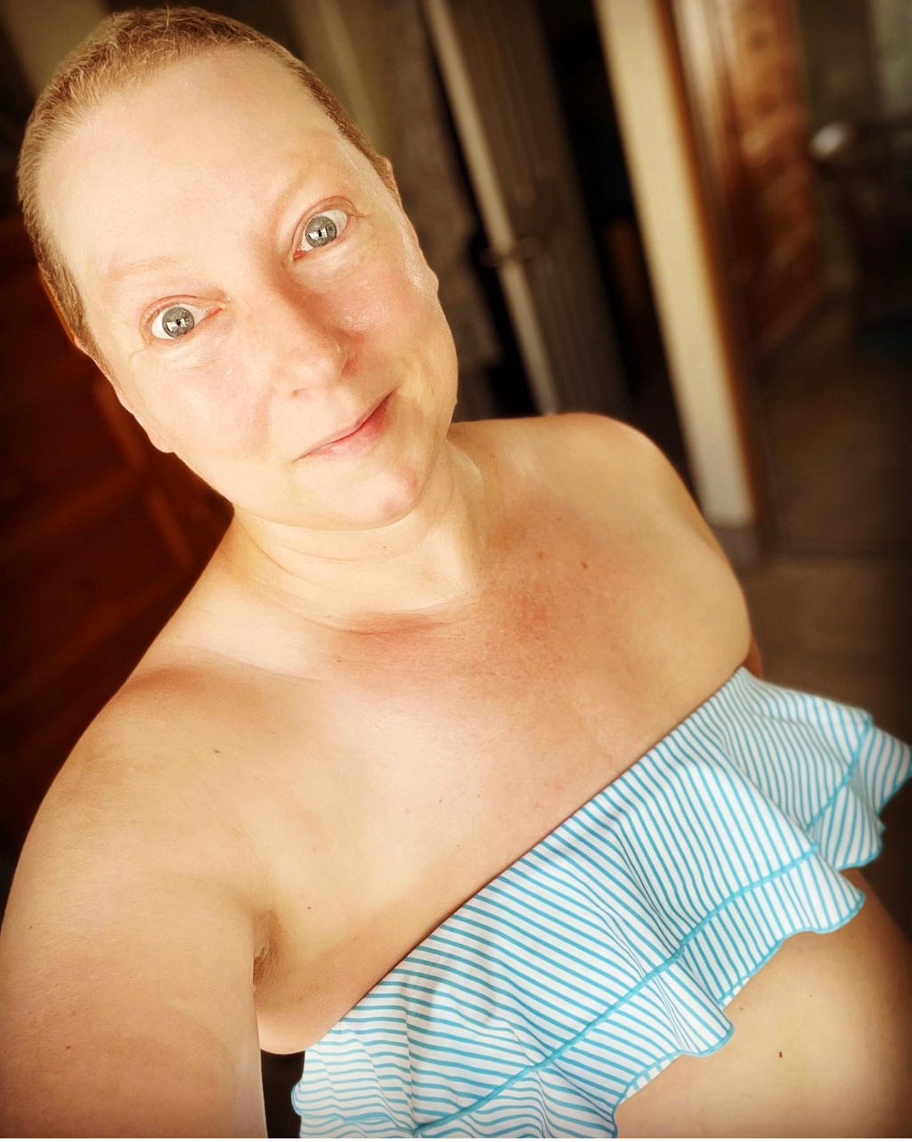 Woman with blue eyes, very short hair and flat chest in a blue and white striped strapless bikini top