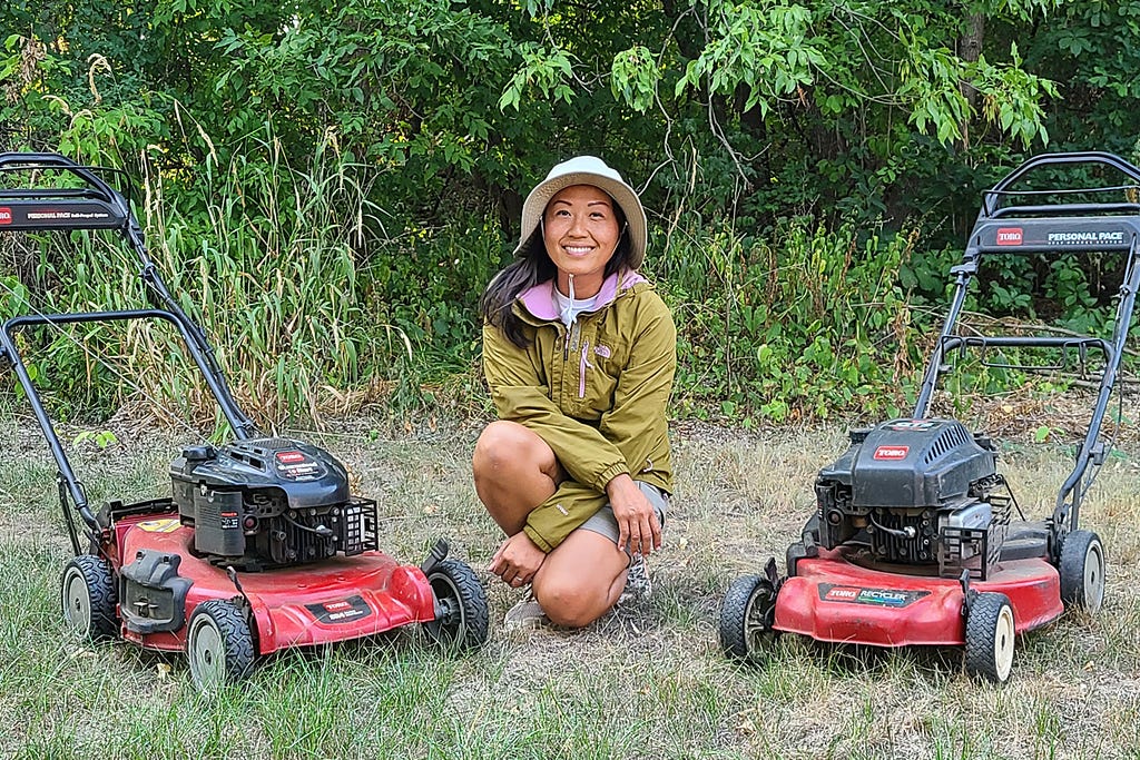 lawnup creator sits inbetween two lawn mowers on the grass