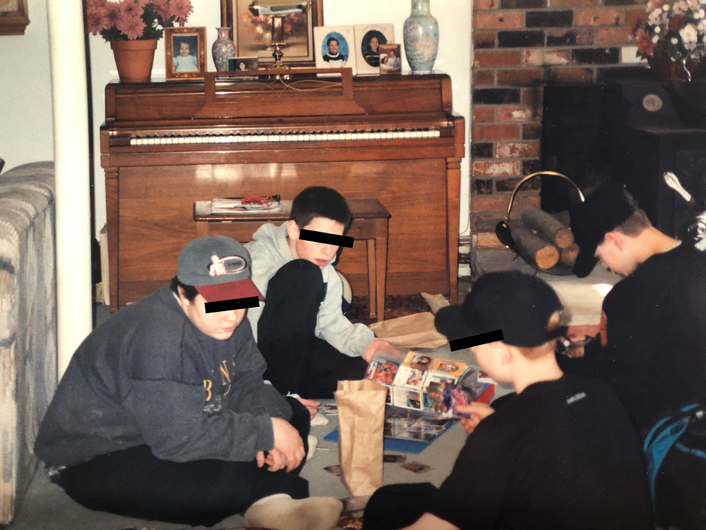 Four teenage boys sitting on the floor and trading sports cards