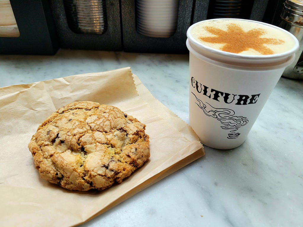 Chocolate chip cookie and coffee drink on marble counter