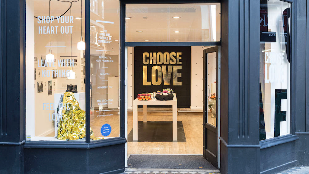 Shop fron showing “Choose Love” poster inside.