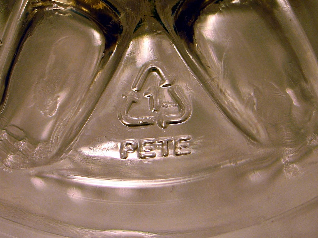 A close up of a plastic bottle with a triangle logo with a 1 in the middle and PETE below