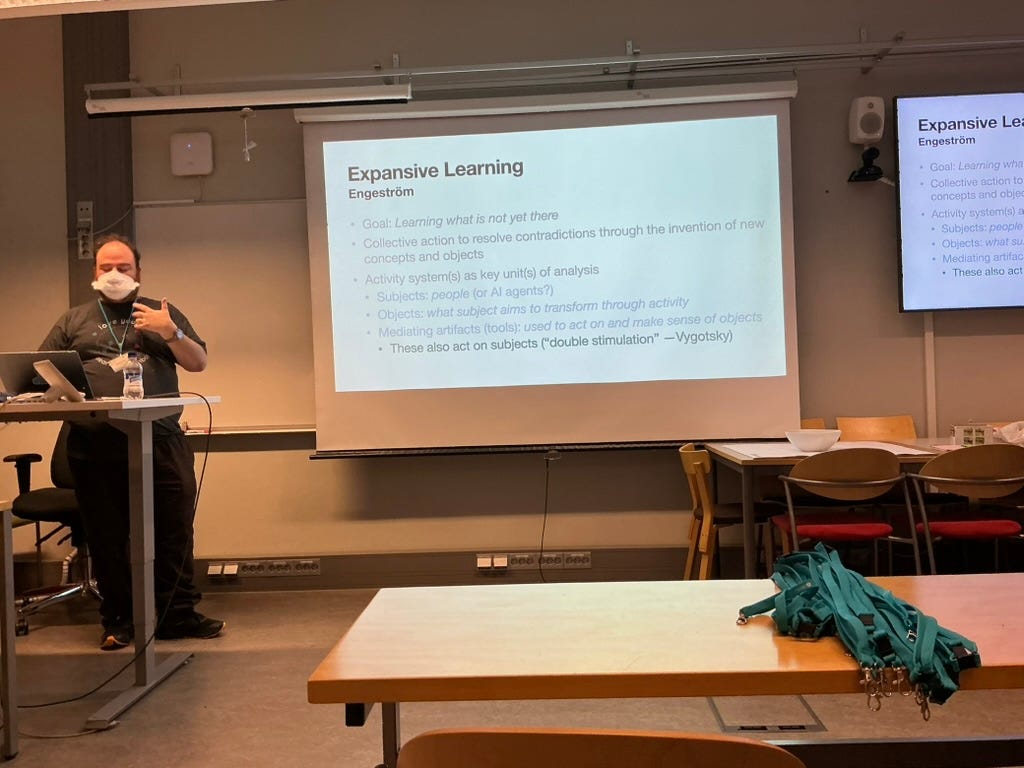 Ben at a disk with a projector screen that says Expansive Learning, Engstrom.