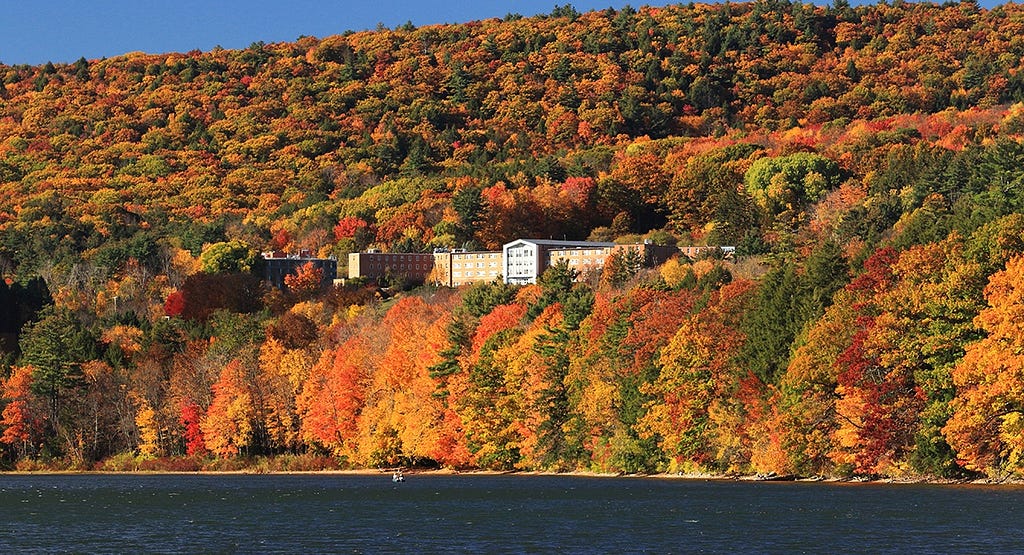 The red brick main building of the Kripalu Center for Yoga and Health, nestled on a hill of the Massuchetts Berkshires, surrounded by trees in their autum colors.