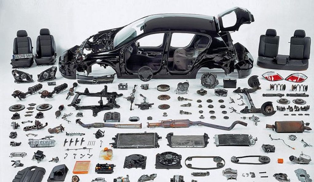 A picture of a car, broken down in pieces, with all the parts laid out