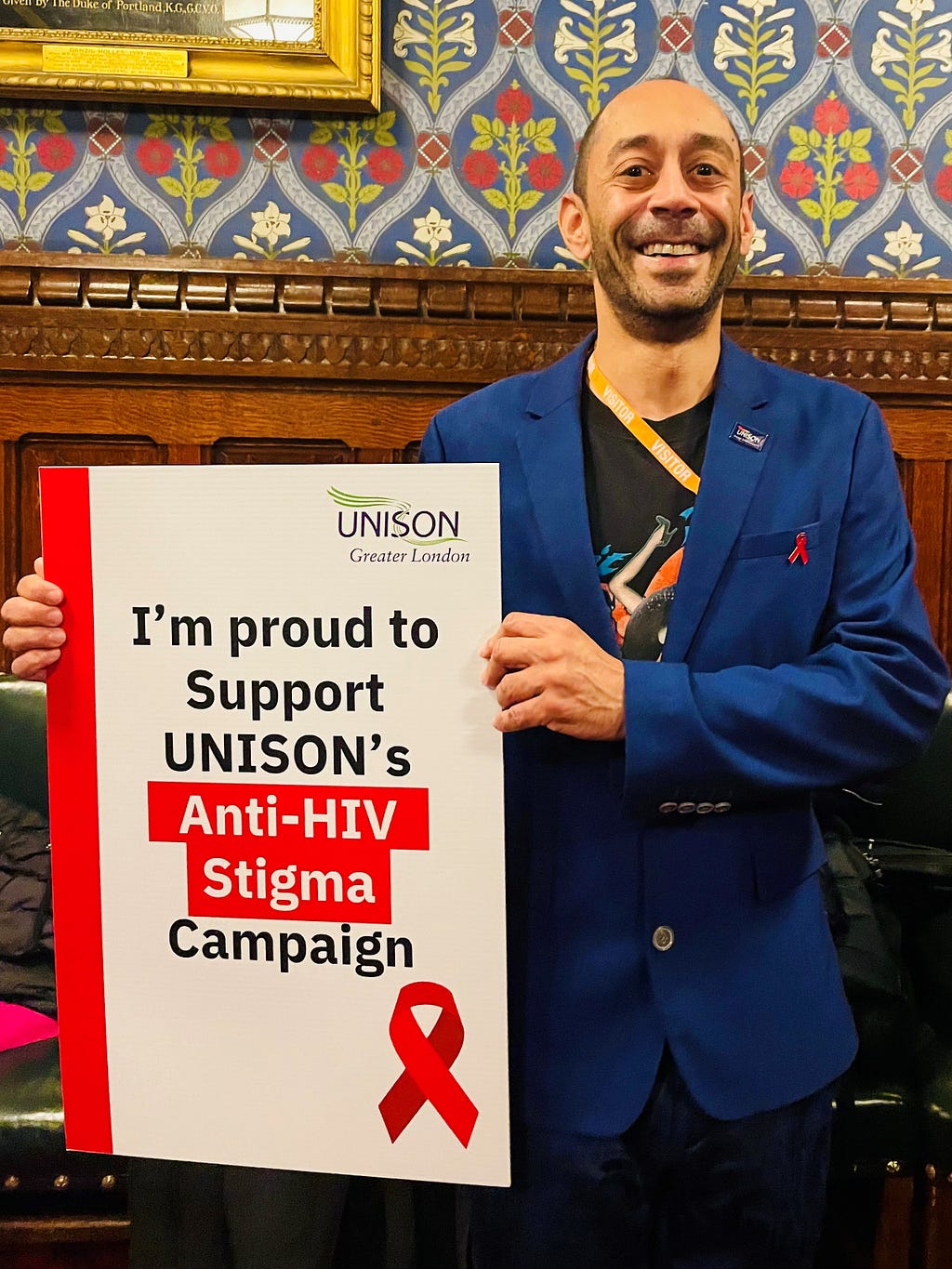 Ant Babajee holds a placard that says: I’m proud to support UNISON’s anti-HIV stigma campaign