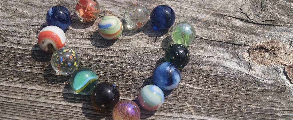 Multi-colored marbles placed in the shape of a heart on top of a wooden bench